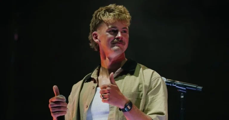 Imagen de Forrest Frank en el escenario de UniteUS con las manos levantadas, audiencia de fondo, iluminación dramática que capture el momento emotivo del testimonio